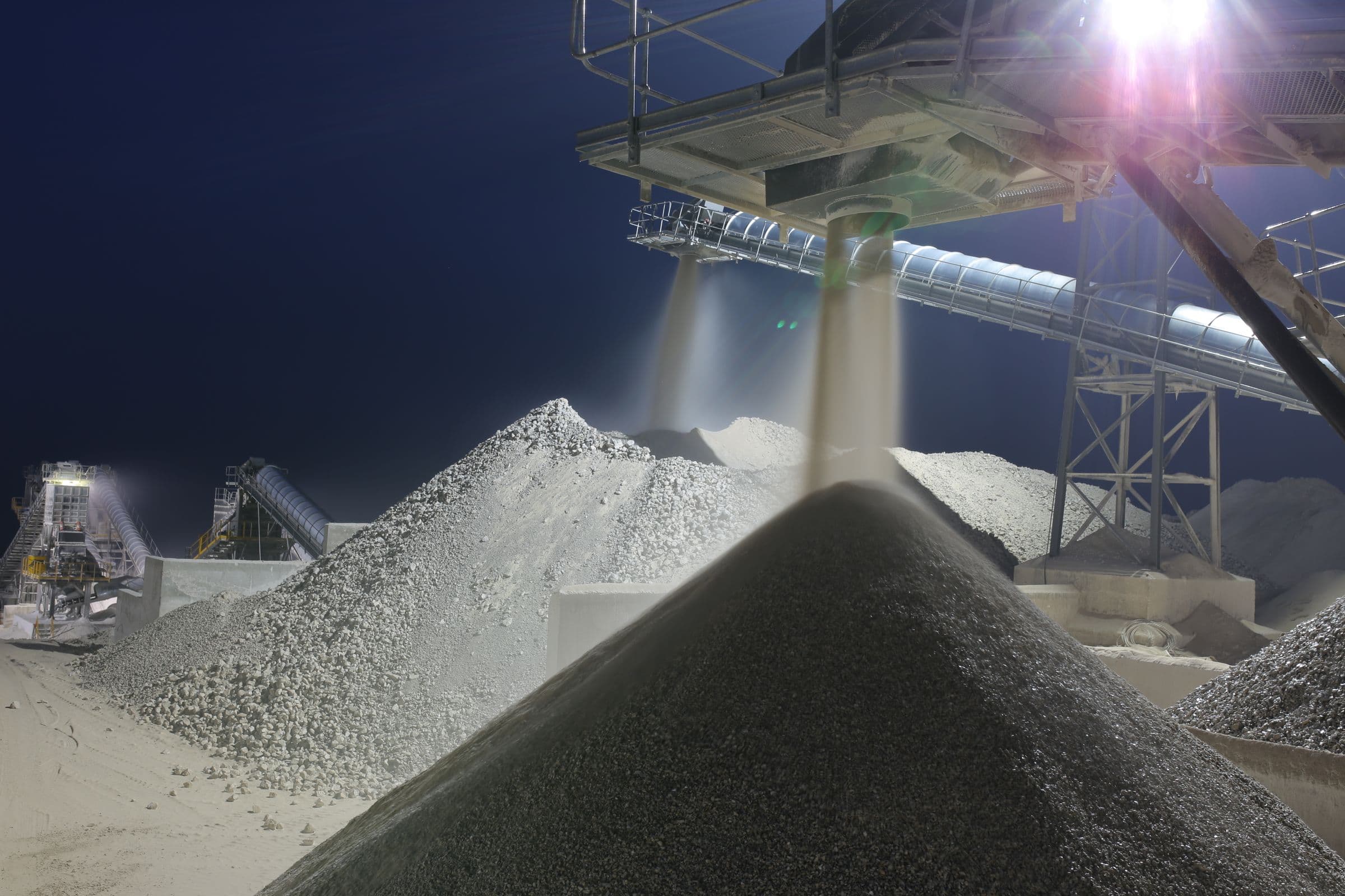 Crushing and screening plant running at night, conveyors discharging processed material to stockpiles.