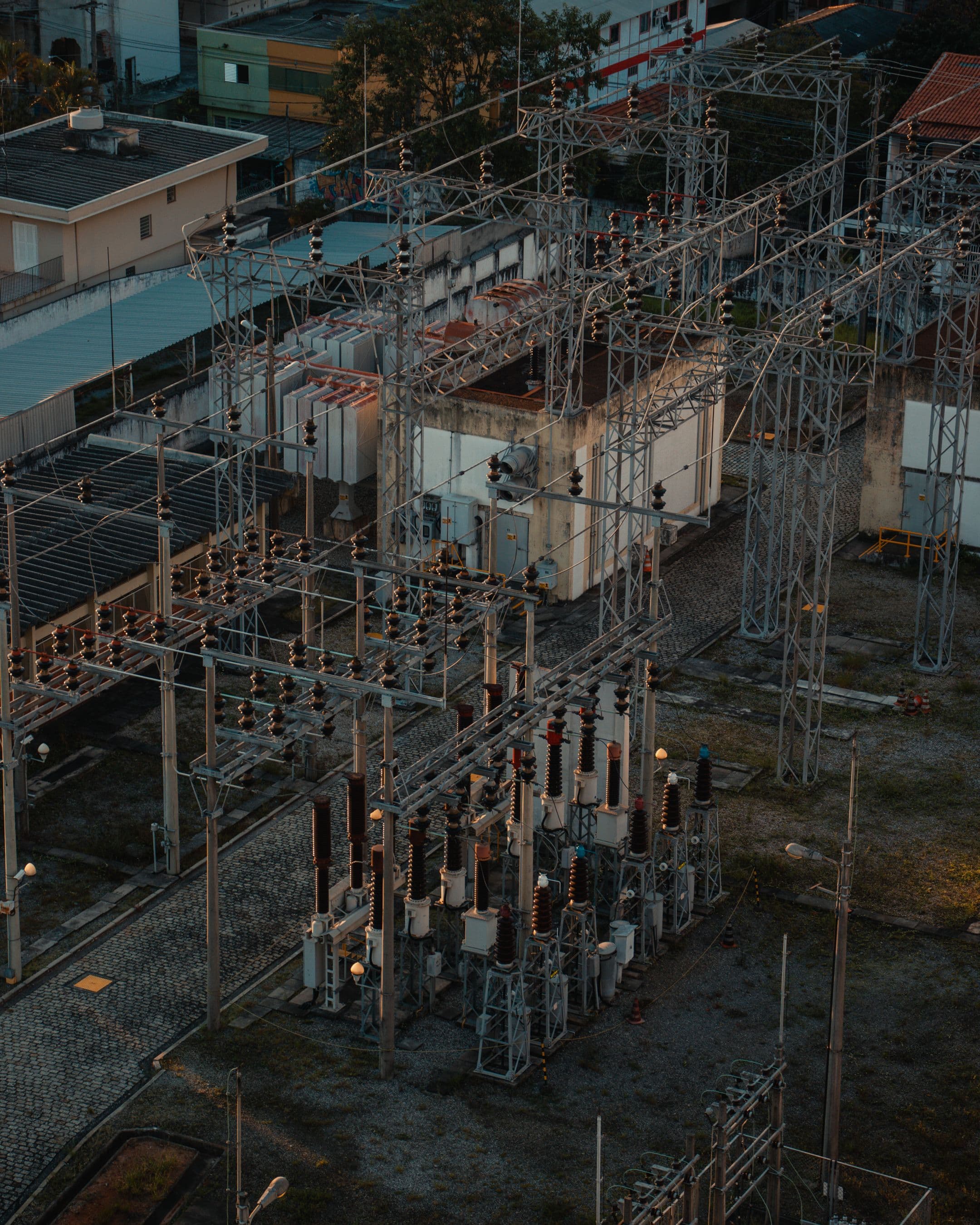 Distribution substation set inside a city neighborhood at dusk, the everyday territory of municipal power systems.