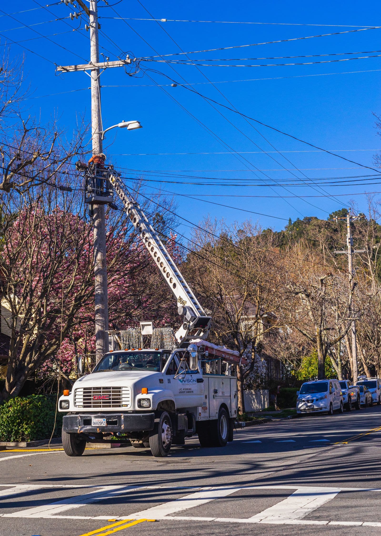 A utility bucket truck working overhead distribution along a street.