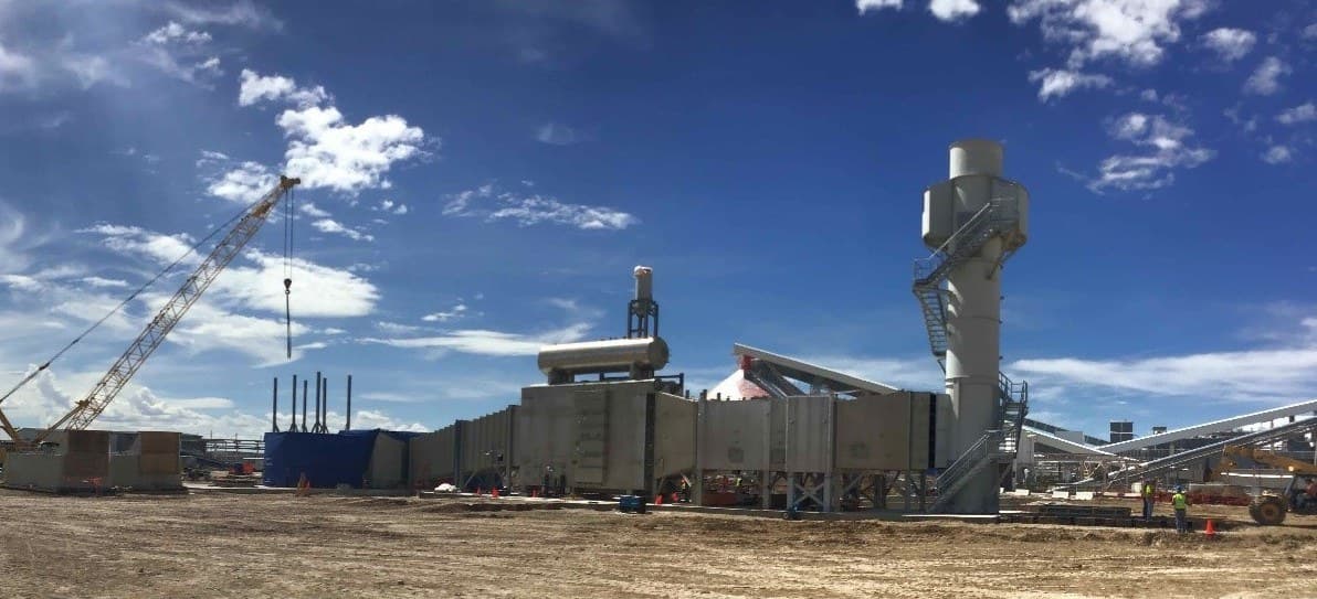A heat recovery steam generator under assembly, stack and crane on site.