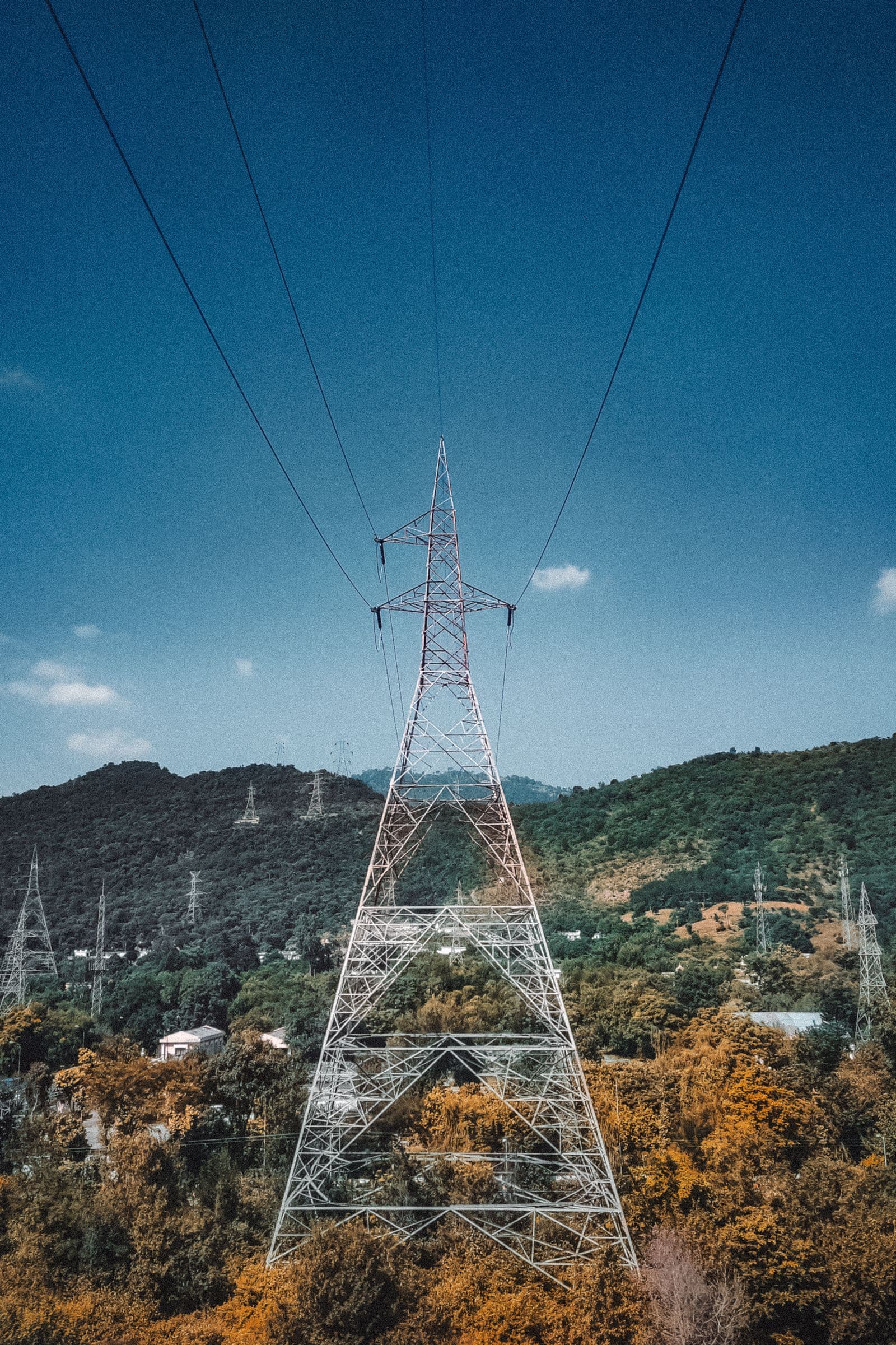 A high-voltage transmission tower against Intermountain terrain.