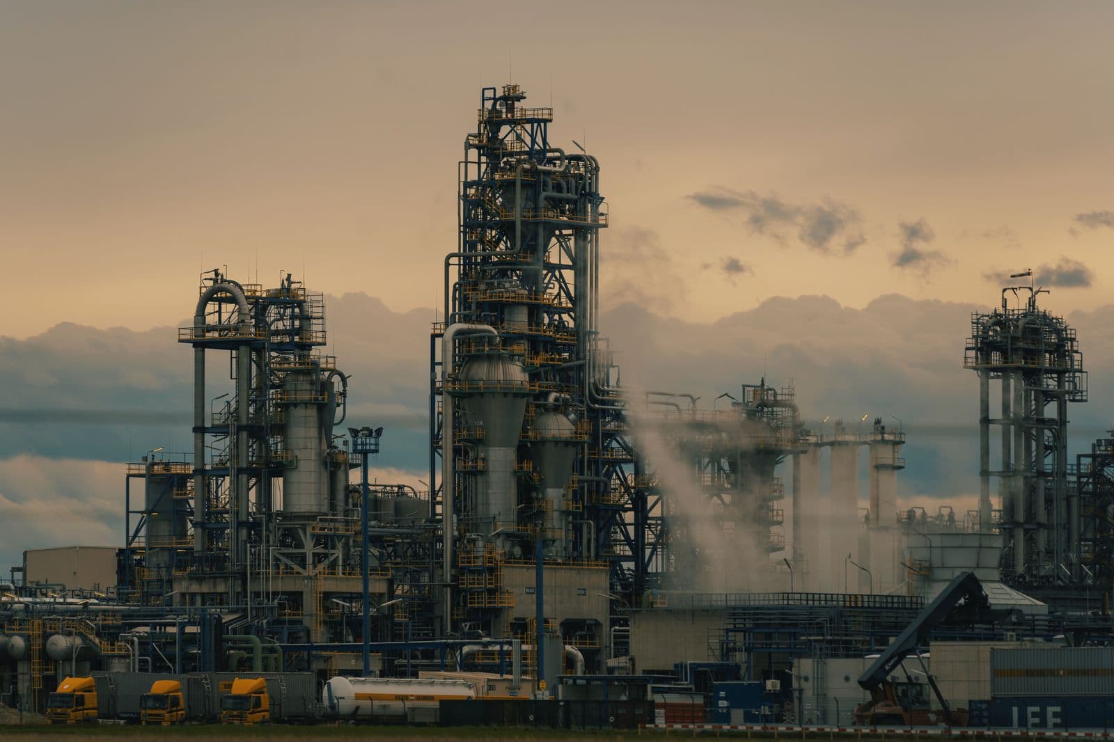 Refinery process towers and piping at dusk, representative of ICPE oil and gas work.