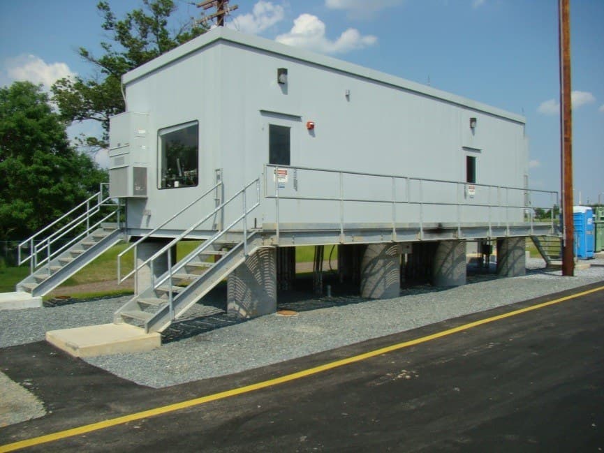 A prefabricated electrical building on piers with access stairs.
